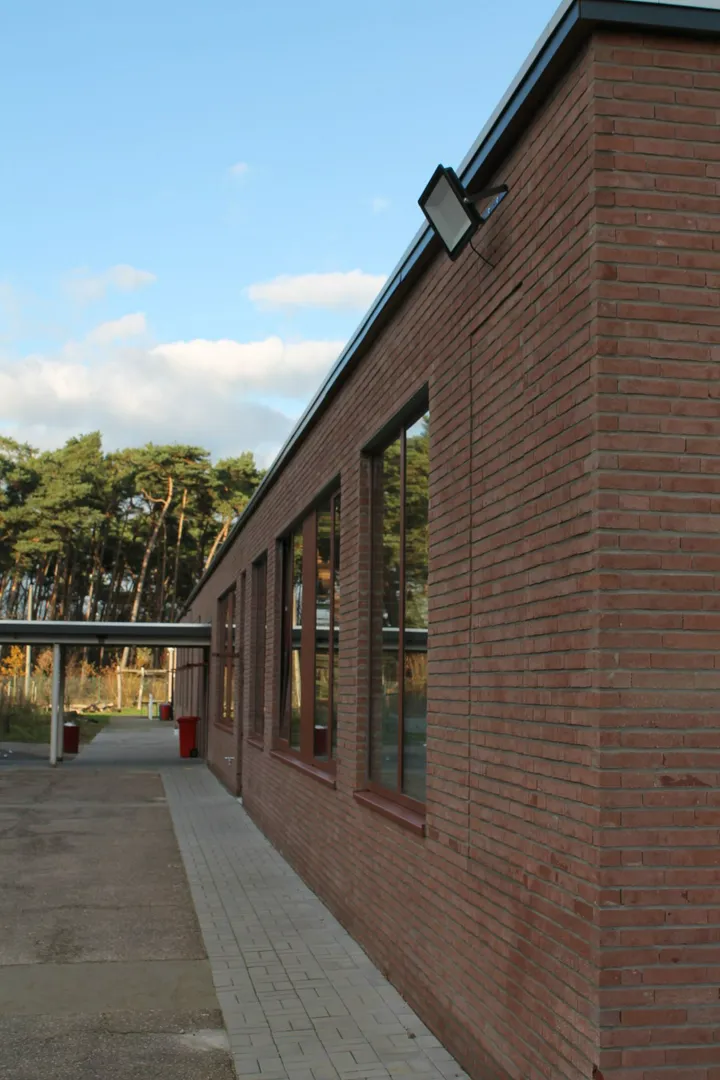 Elewacja domu z czerwonej cegły z oknami, podjazdem i zadaszonym wejściem