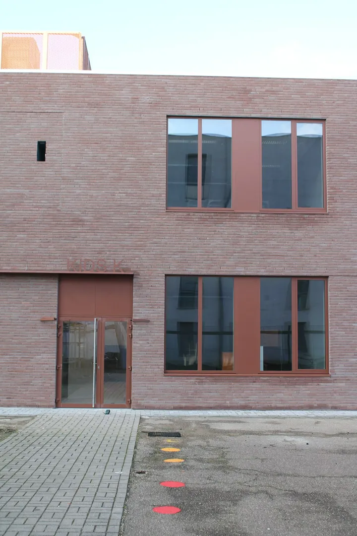 Elewacje domu: klinkierowa fasada z dużymi oknami, drzwiami i kostką brukową przy wejściu