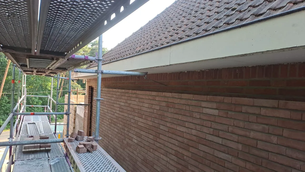 Rusztowanie przy murowanej elewacji domu z cegły i dachu pokrytego dachówką Elewacje domu