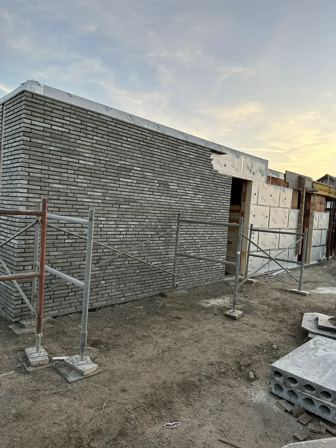 Elewacje domu z szarej cegły klinkierowej w trakcie montażu na rusztowaniu