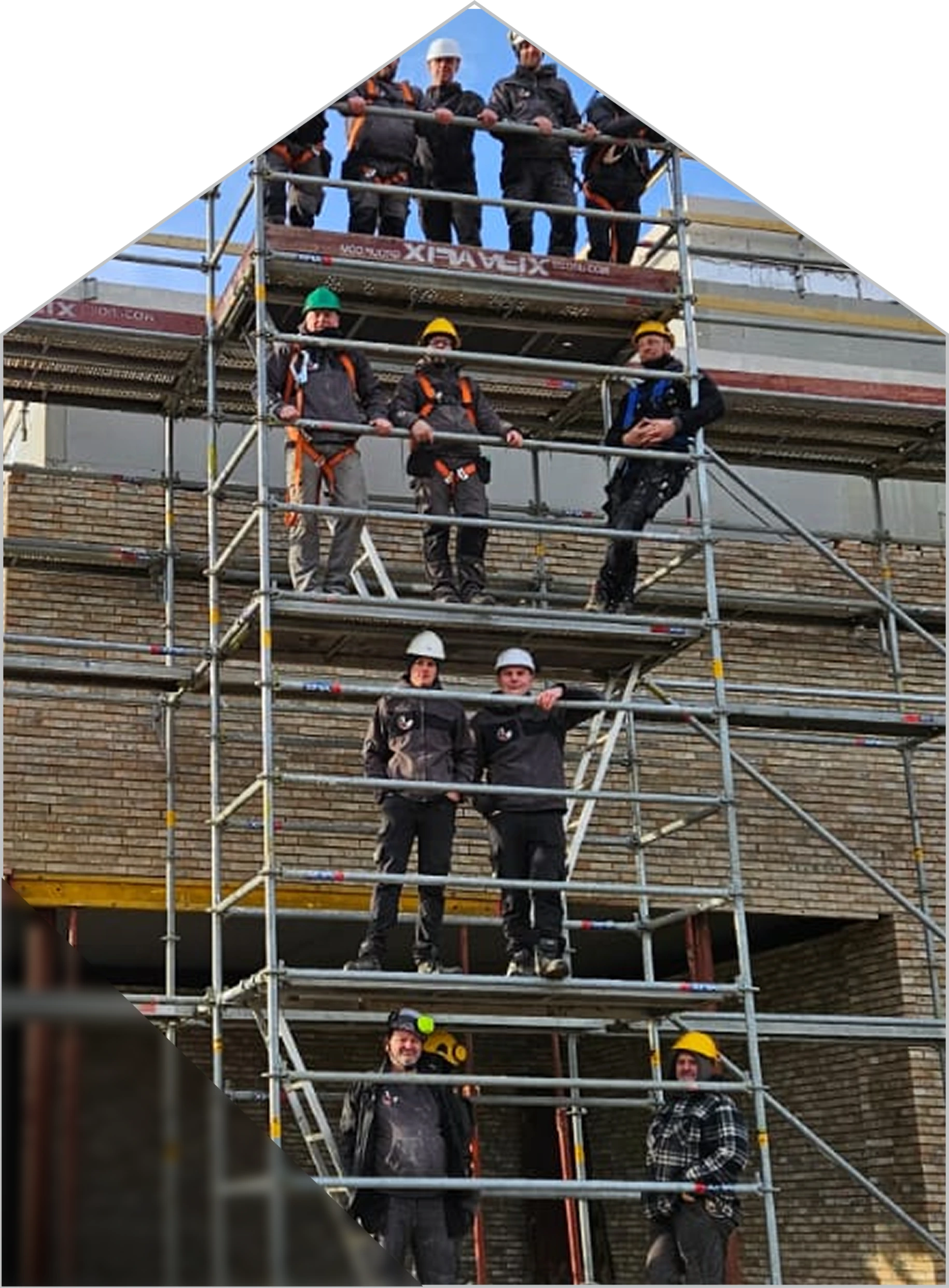 Grupa robotników na rusztowaniu przy elewacji domu w trakcie prac