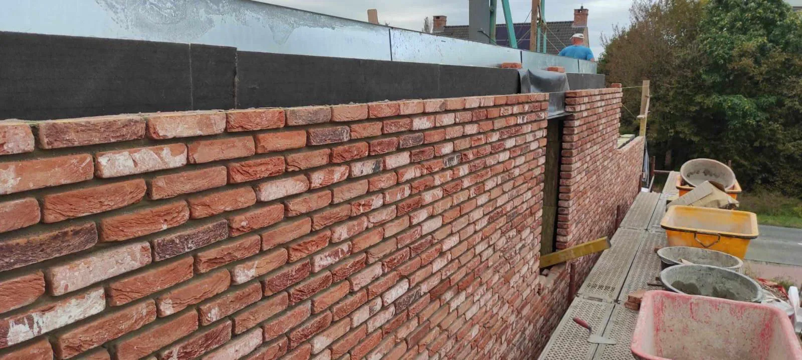 Elewacje domu murowana z czerwonej cegły na rusztowaniu z tacami i kielnią