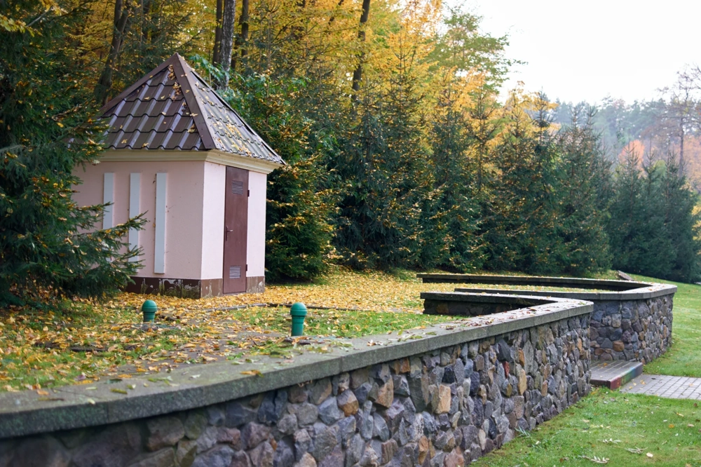 Murki oporowe z kamienia przy niewielkim budynku w otoczeniu zieleni