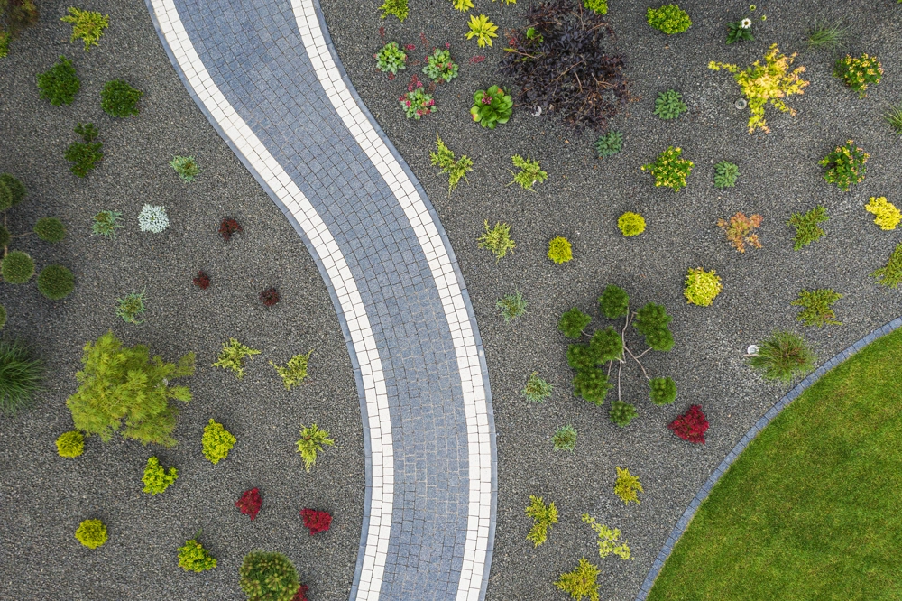 Kręty chodnik z kostki brukowej otoczony żwirowym podłożem z roślinami – Podjazdy i chodniki